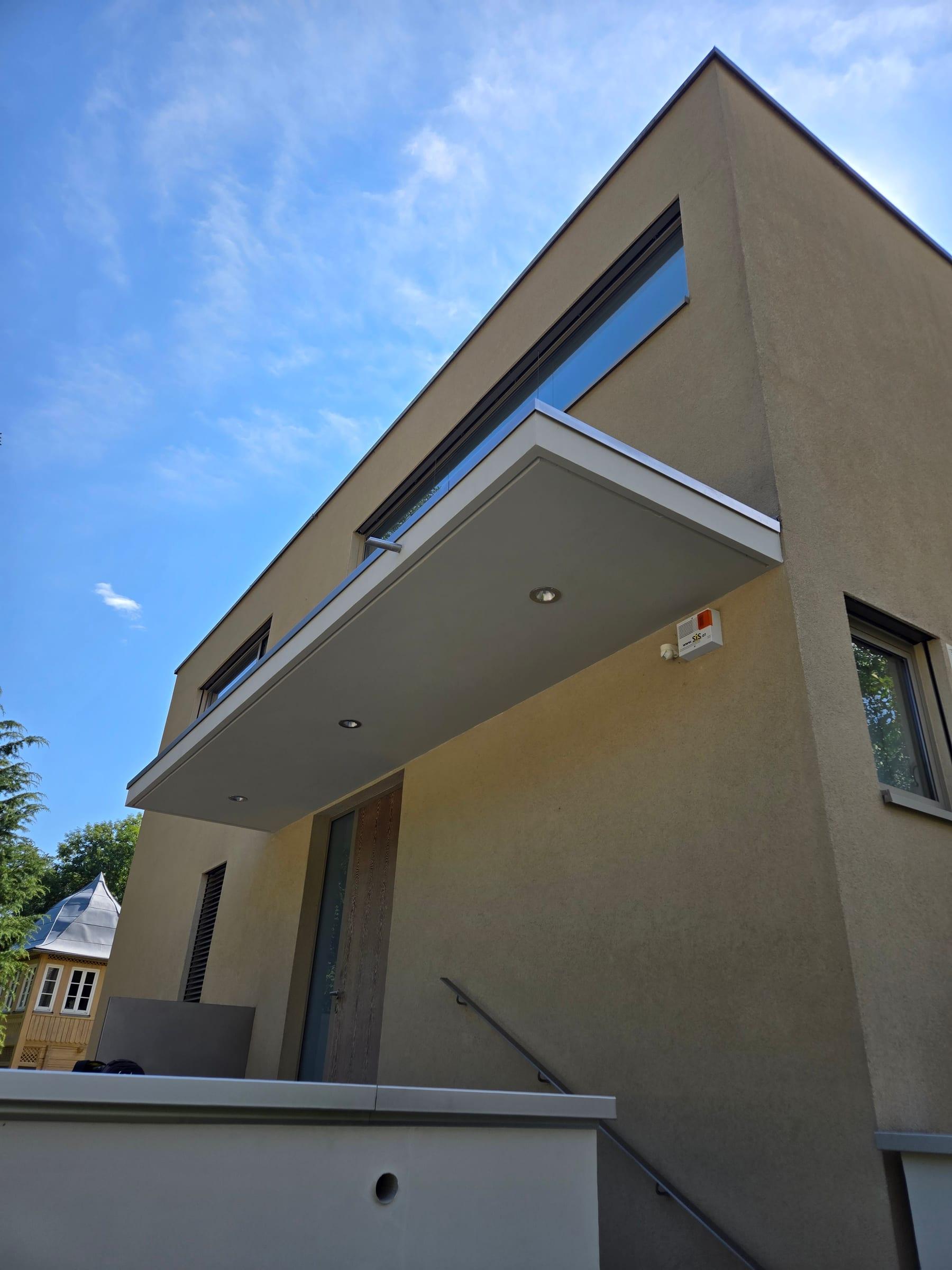 Auskragendes Vordach mit Glasgeländer an einem Wohnhaus